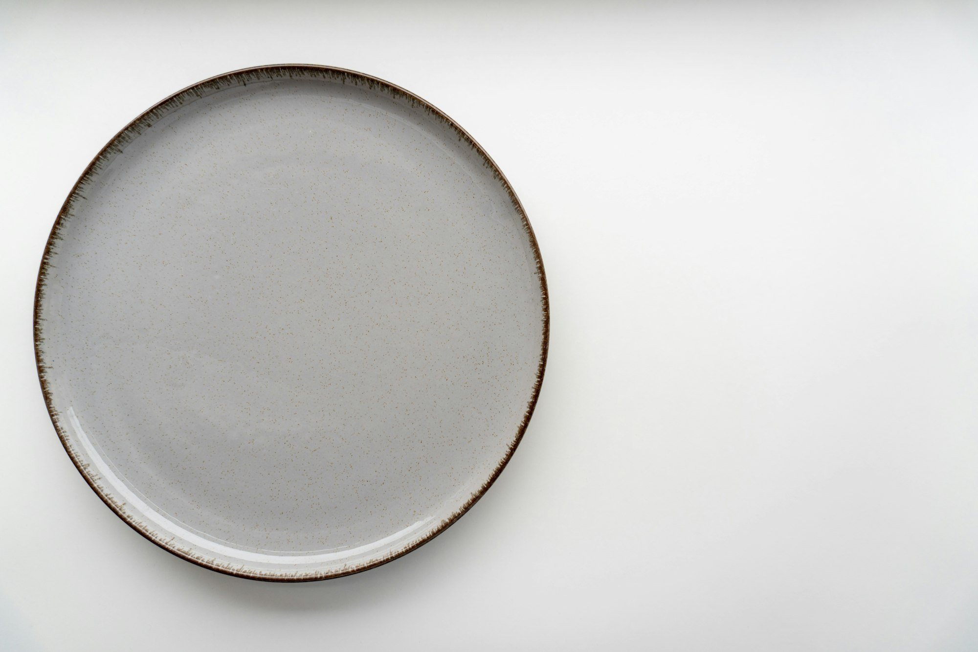 Une assiette plate en grès clair au bord brut