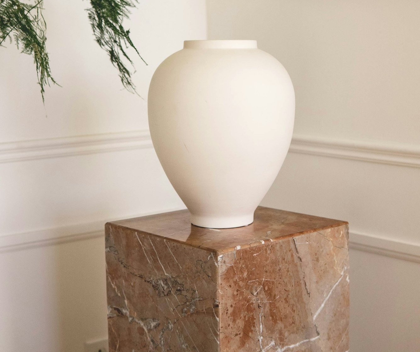 Un vase boule en grès blanc sur un socle en marbre