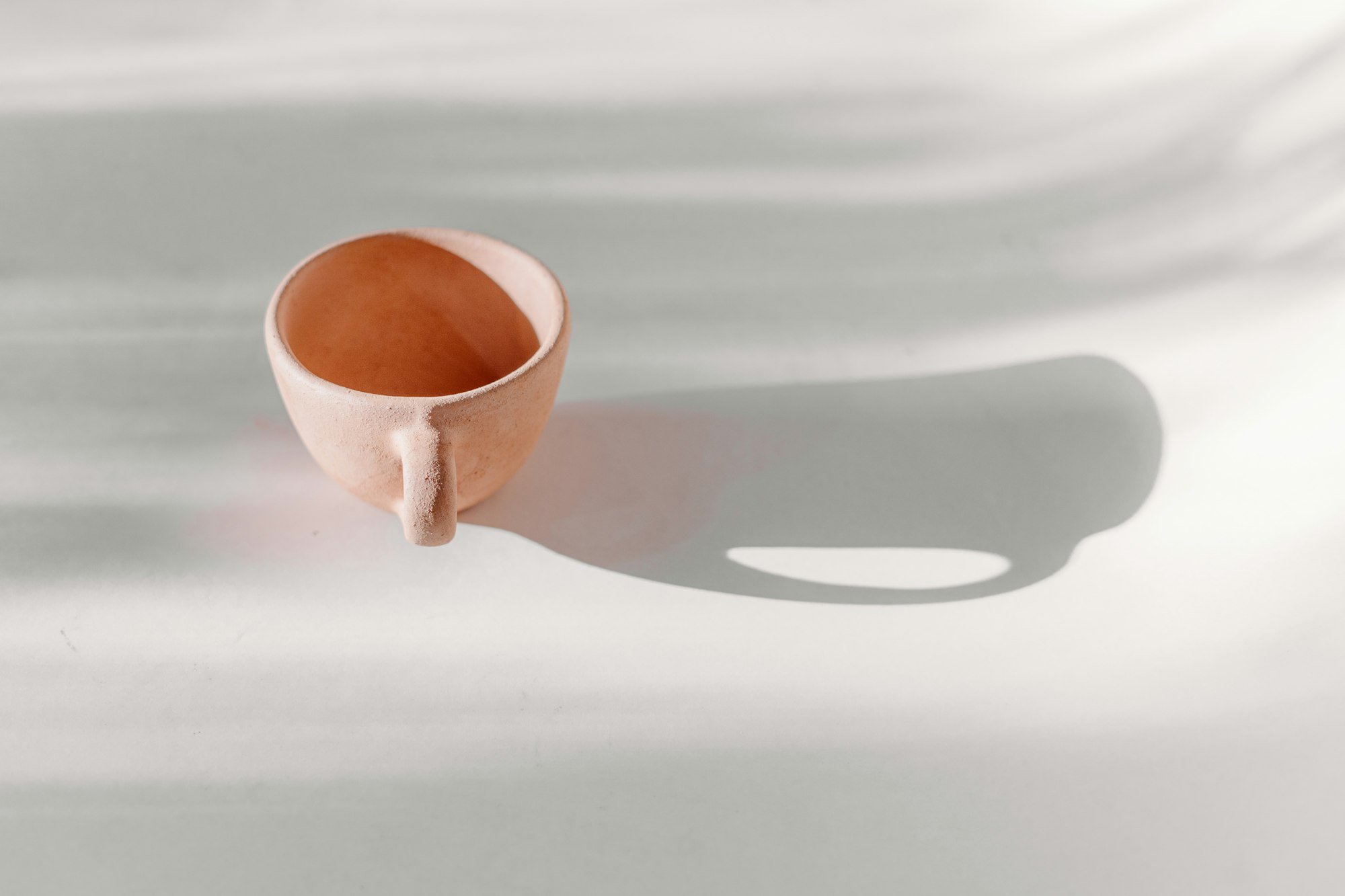 Une tasse en grès couleur argile dans la lumière du matin