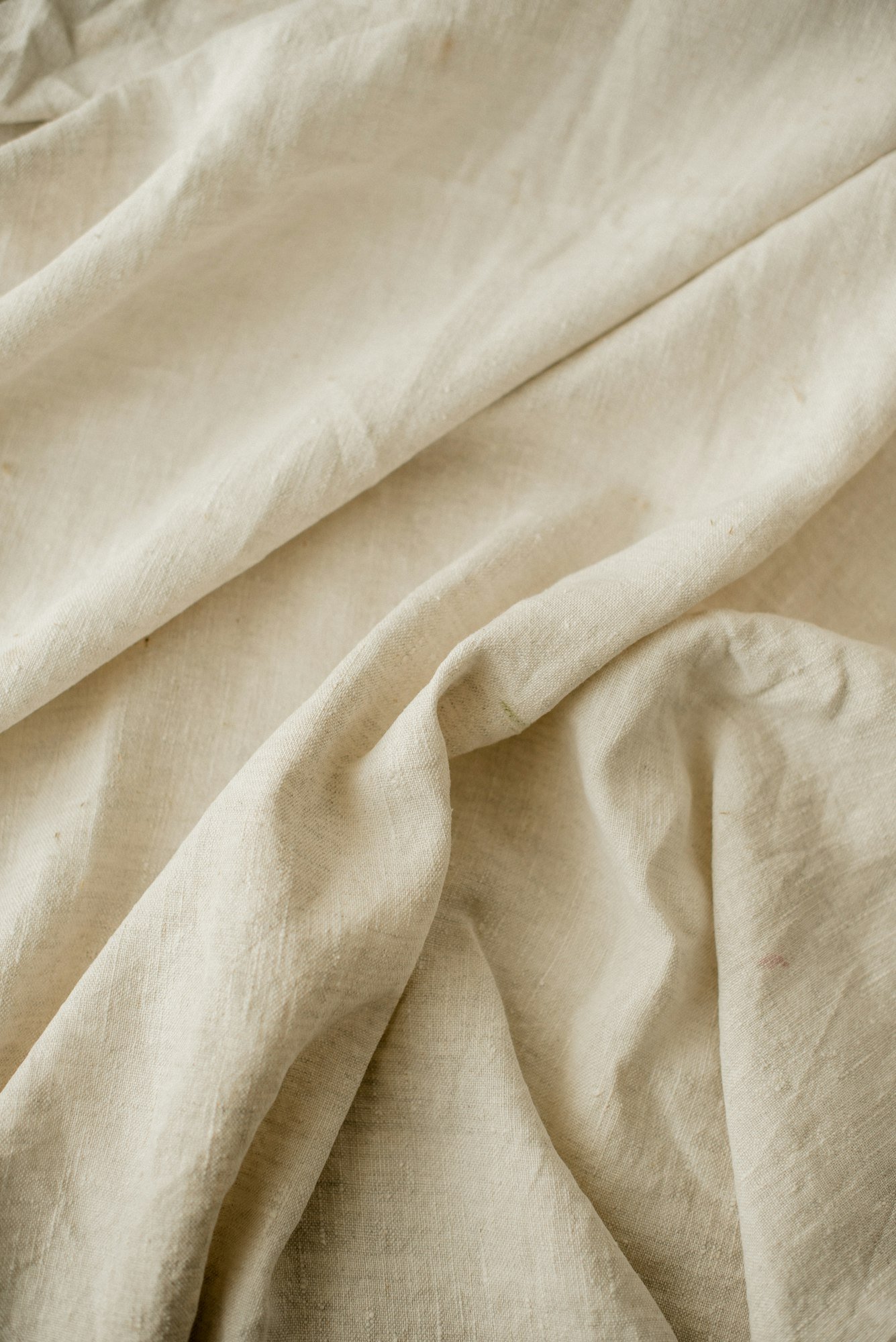 Gros plan sur les plis d’un drap en lin crème